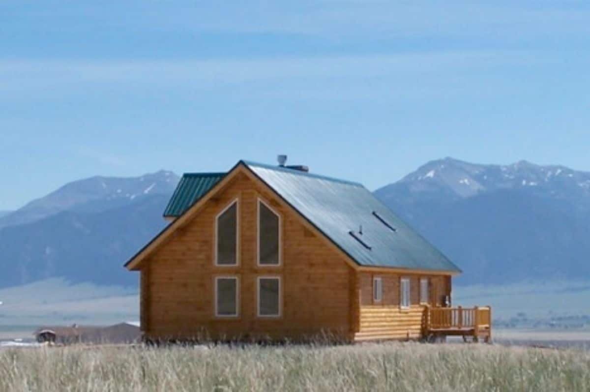 small log cabin surrounded by mountains