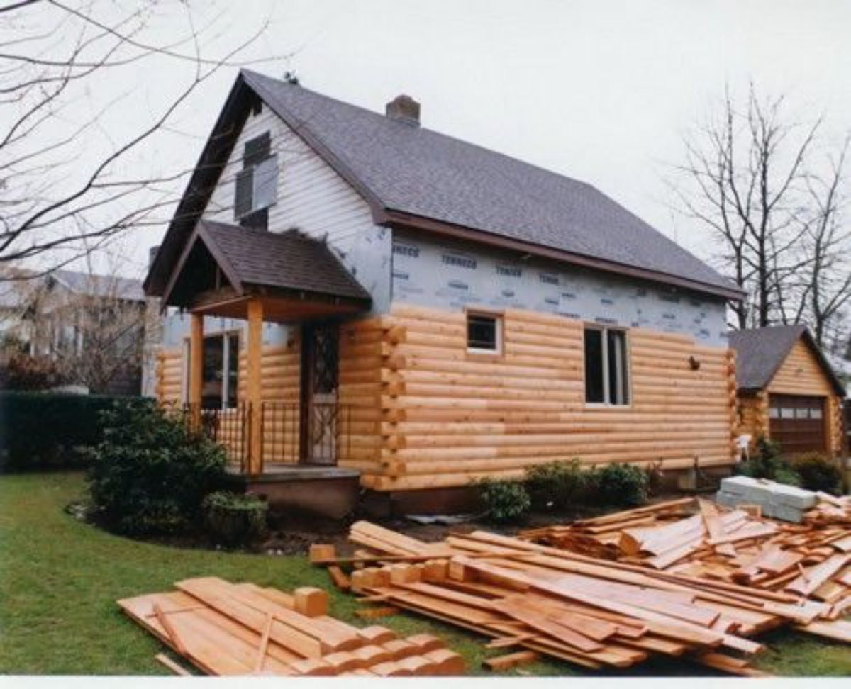 log home with log piles in the yard