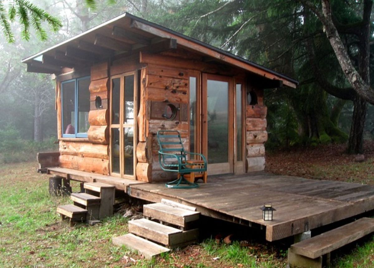 Tiny cabin with outside sitting area in woods