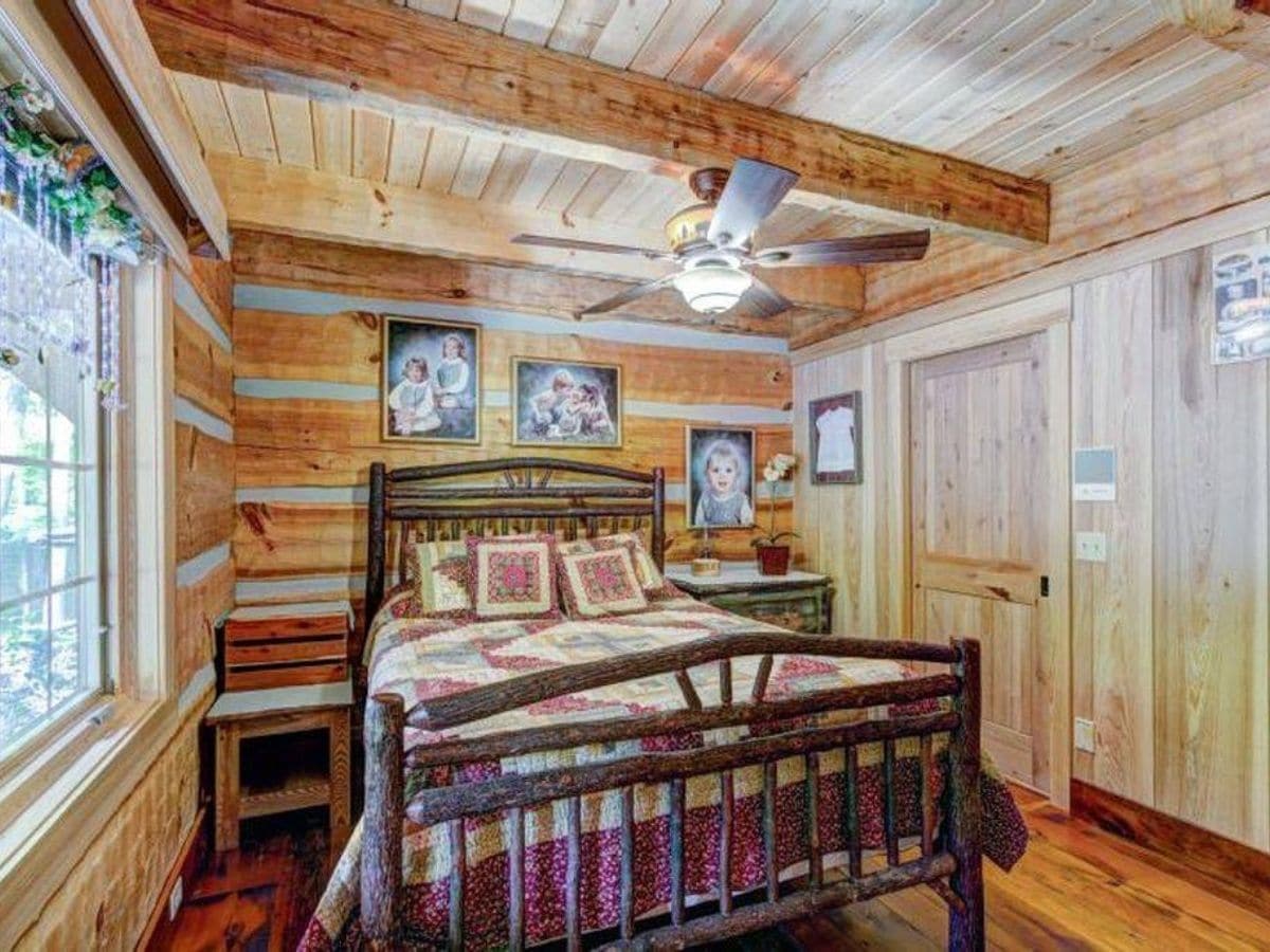 Wood bed frame against log cabin walls with closet on right