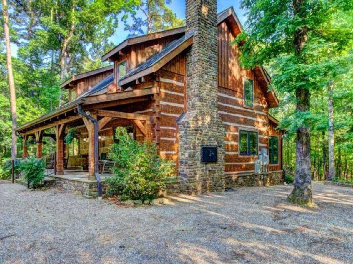log cabin with green shrubs by porch