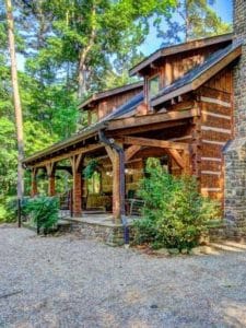 log cabin with green shrubs by porch