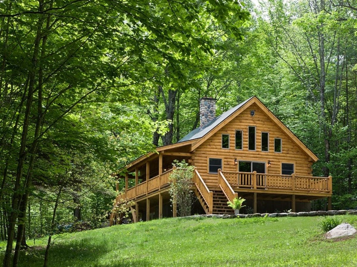 log cabin in green field with trees in background