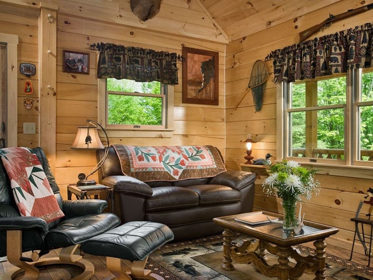 black sofa against log wall under windows