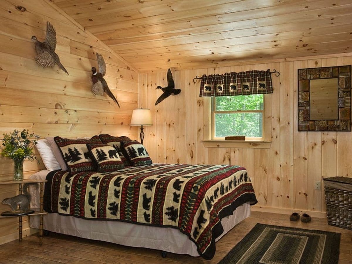bed against log cabin wall with dark rustic blanket