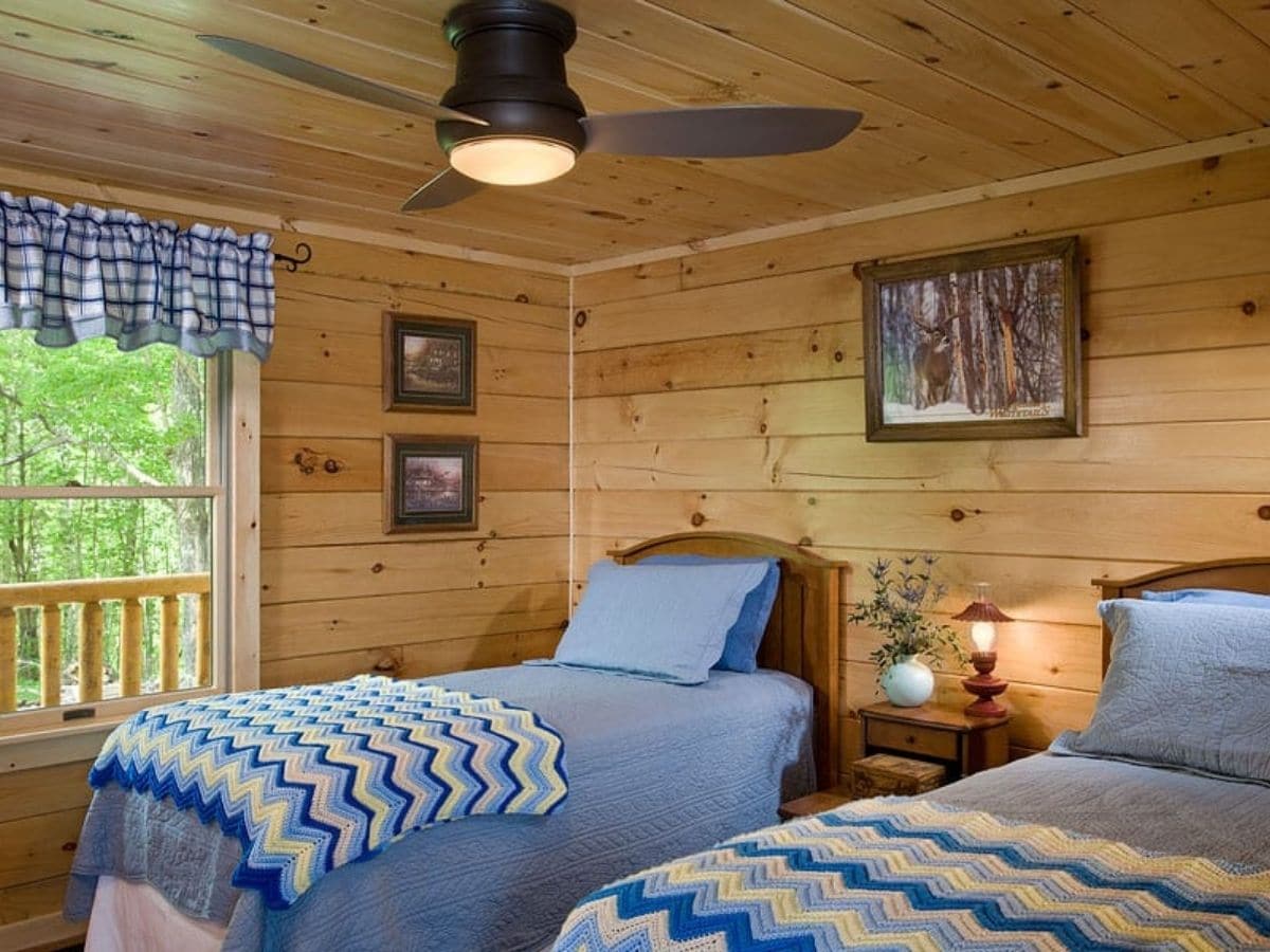 two twin beds in log cabin with blue blankets