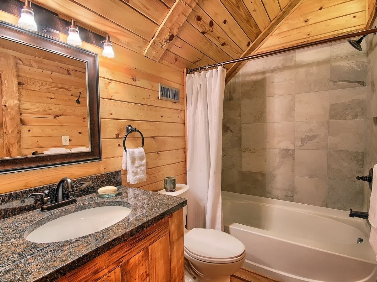 tiled background on bathtub in log cabin bathroom