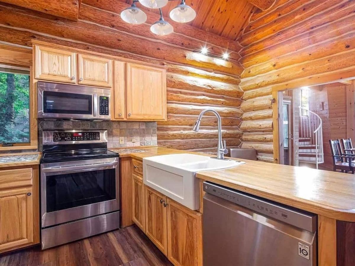 stainless steel dishwasher in foreground with stove in background of kitchen