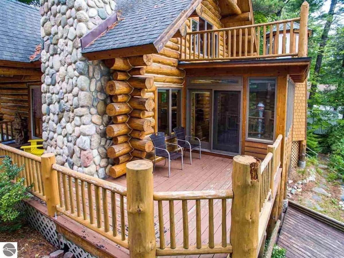 balcony with stone fireplace and log notching on back of home