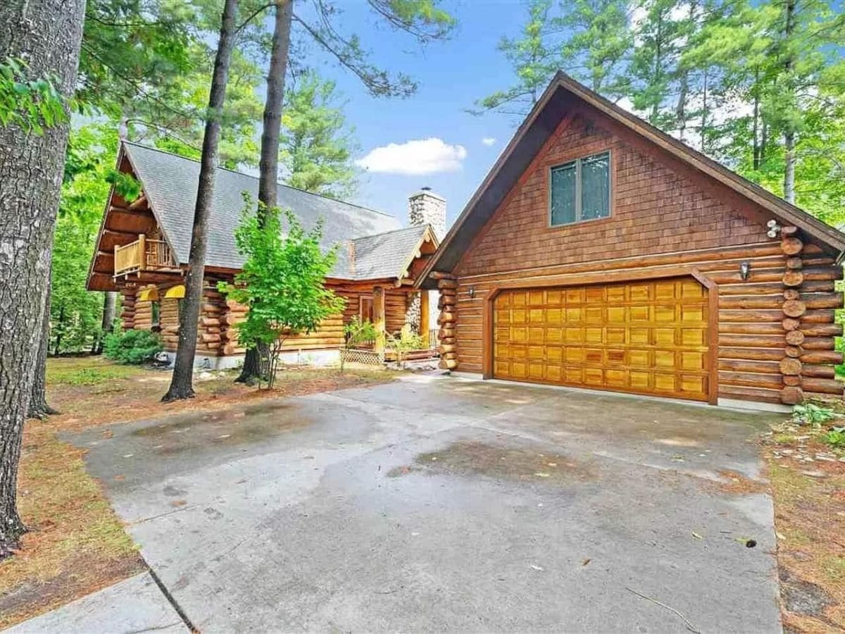 driveway in front of two car log garage and cabin to the left