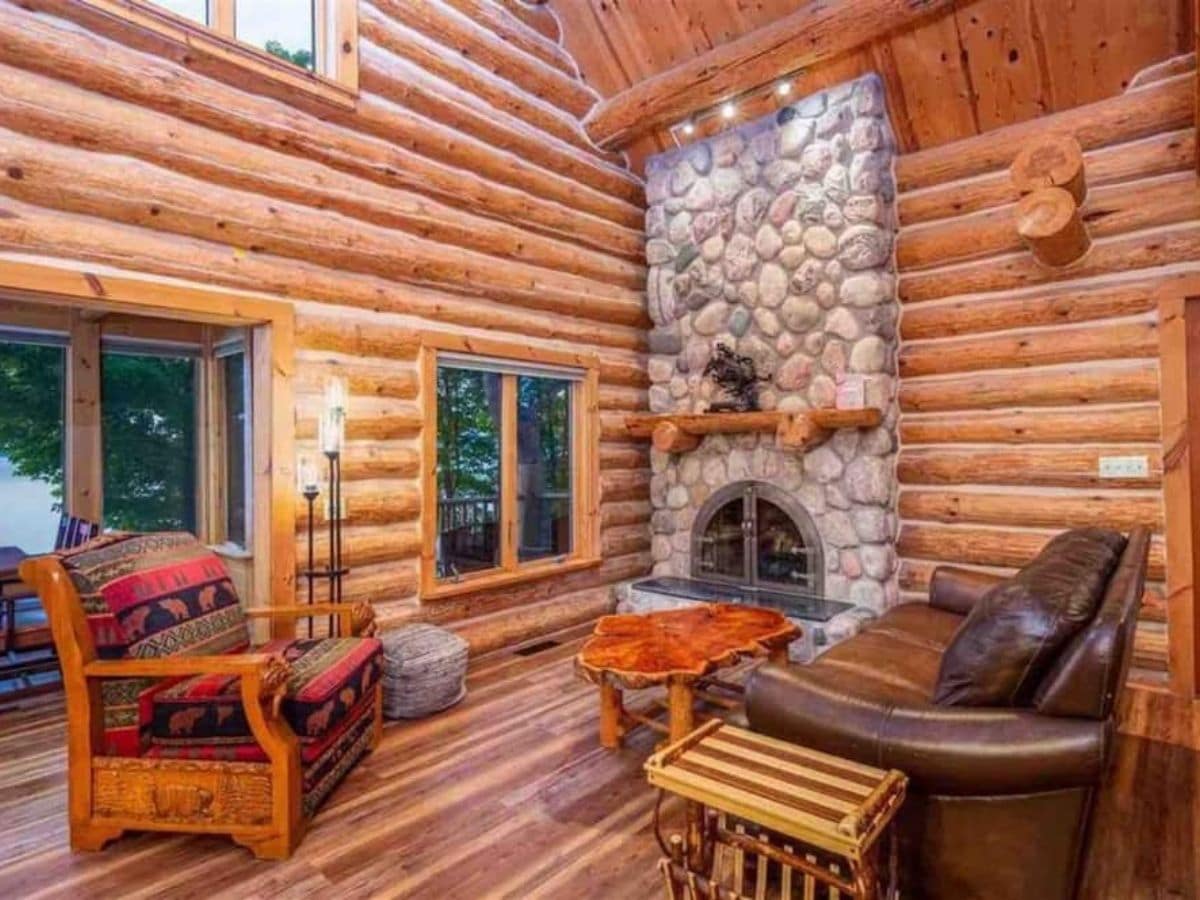 living room in cabin with stone fireplace on back wall