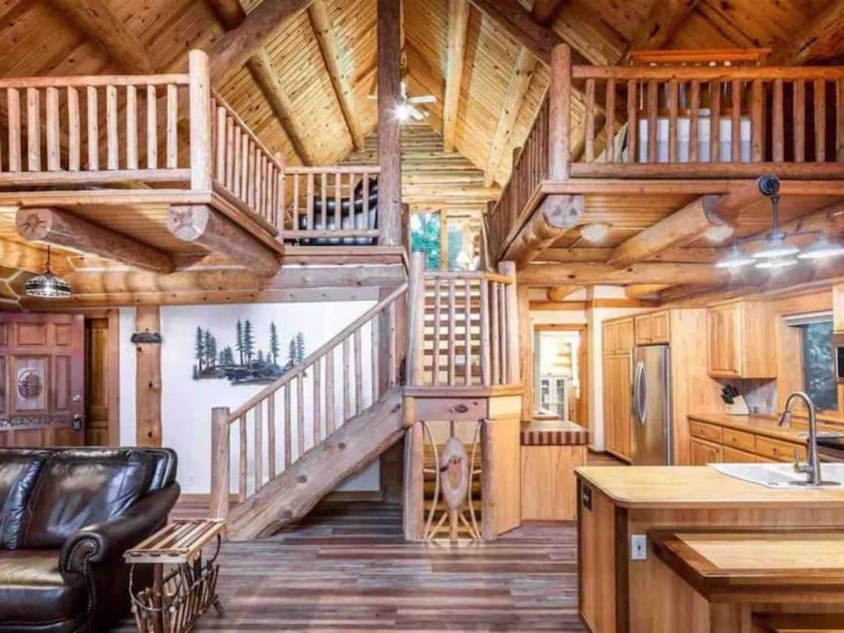 great room inside cabin with stairs in middle and kitchen to right
