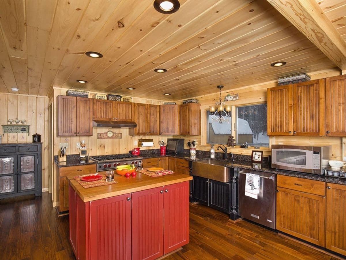 red wood island in kitchen against black and wood cabinets