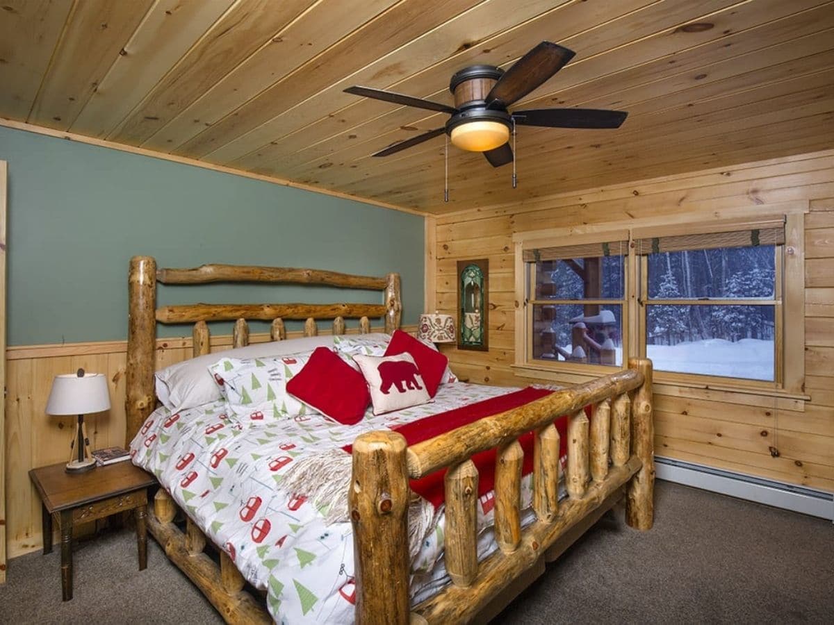 rustic log bed frame in bedroom with green wall and log trim