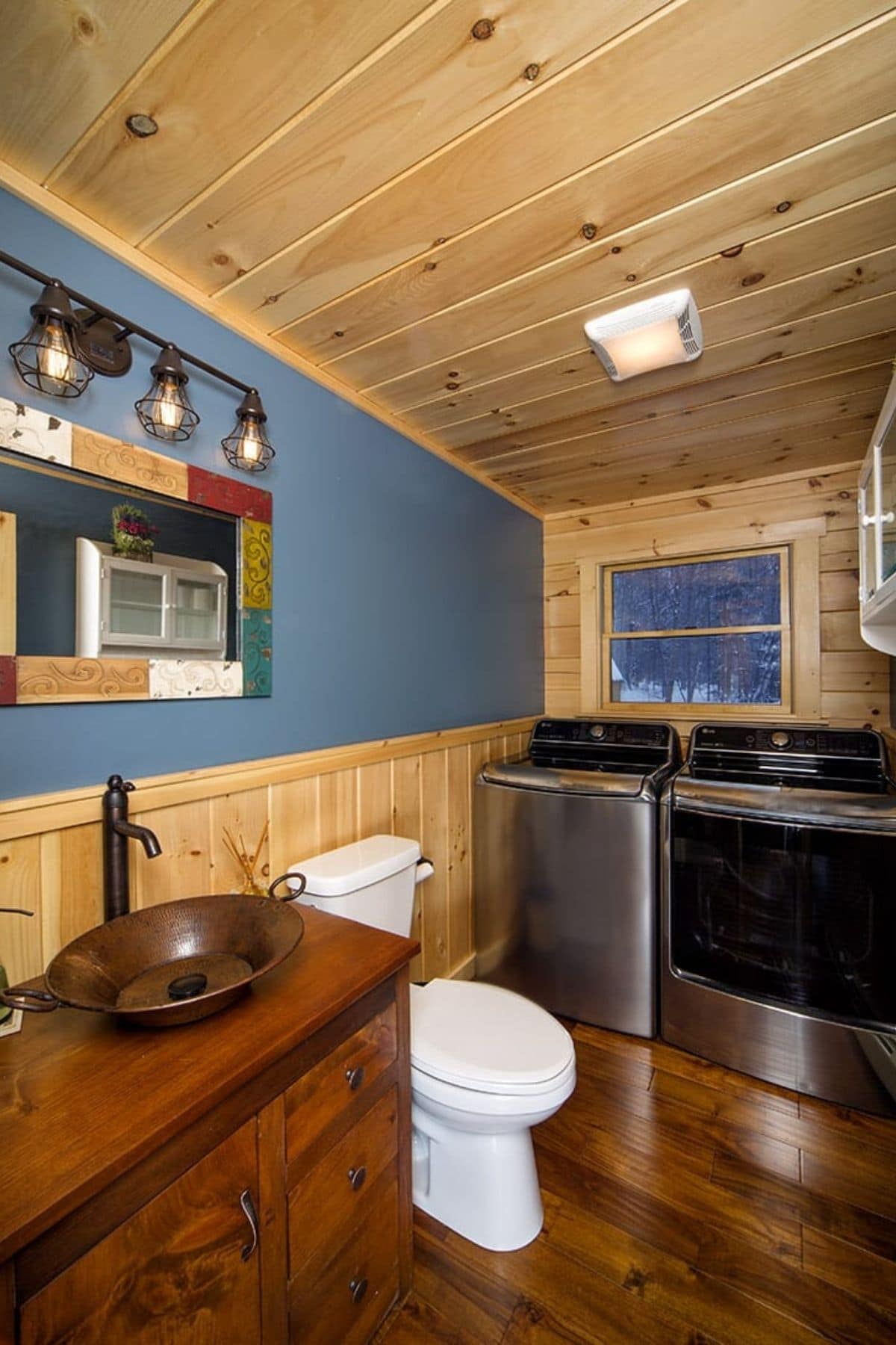 blue wall above sink in log cabin bathroom with washer and dryer against wall