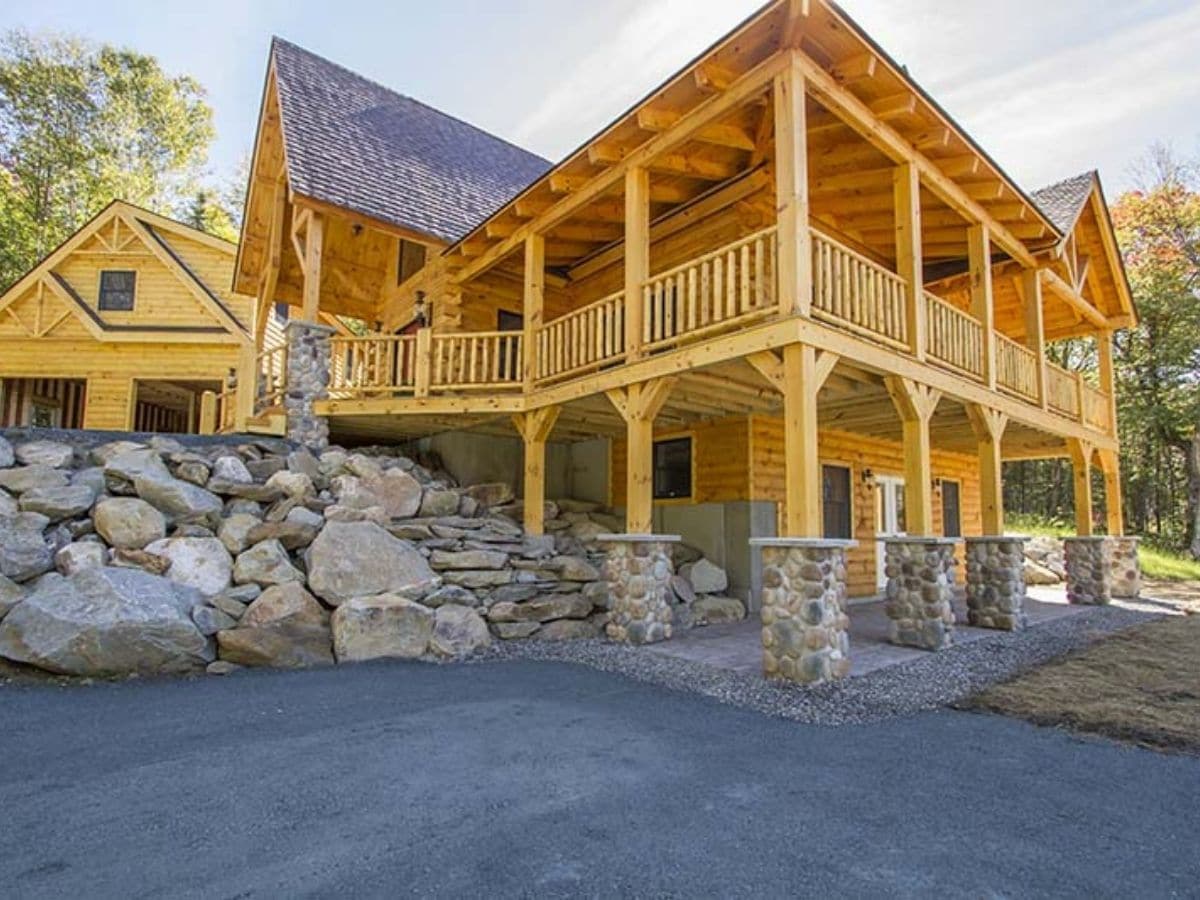 side of log cabin with stone columns at base of walk out basement