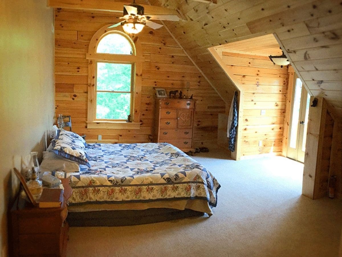 bed under rafters of log cabin