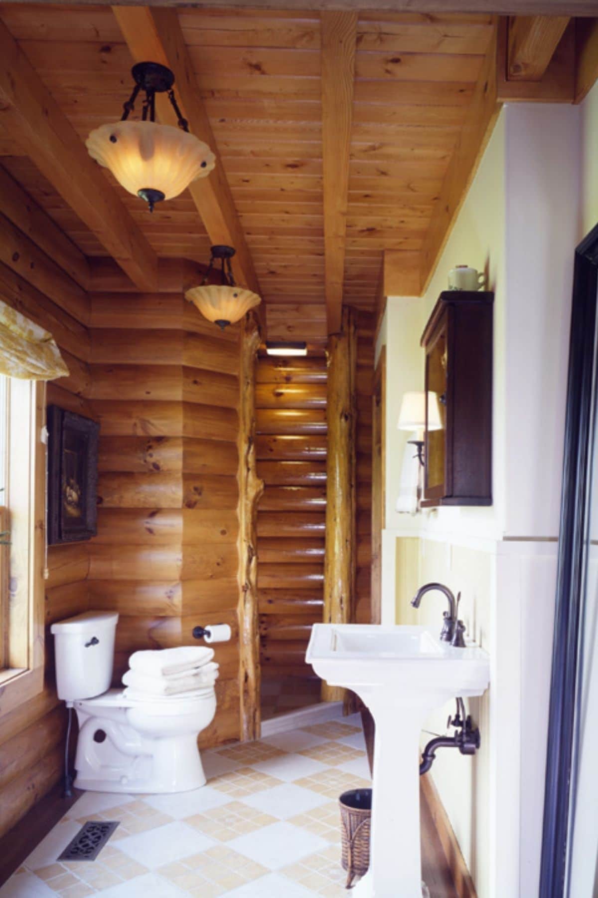white pedastal sink against white wall in log cabin bathroom