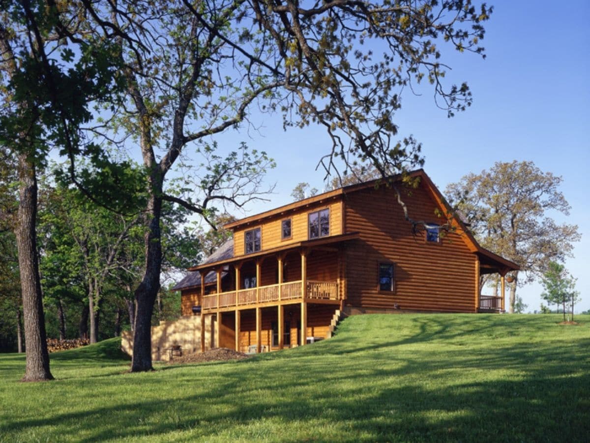 back of log cabin showing balconies on green lawn