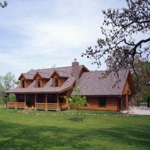 log cabin with attached garage in green field