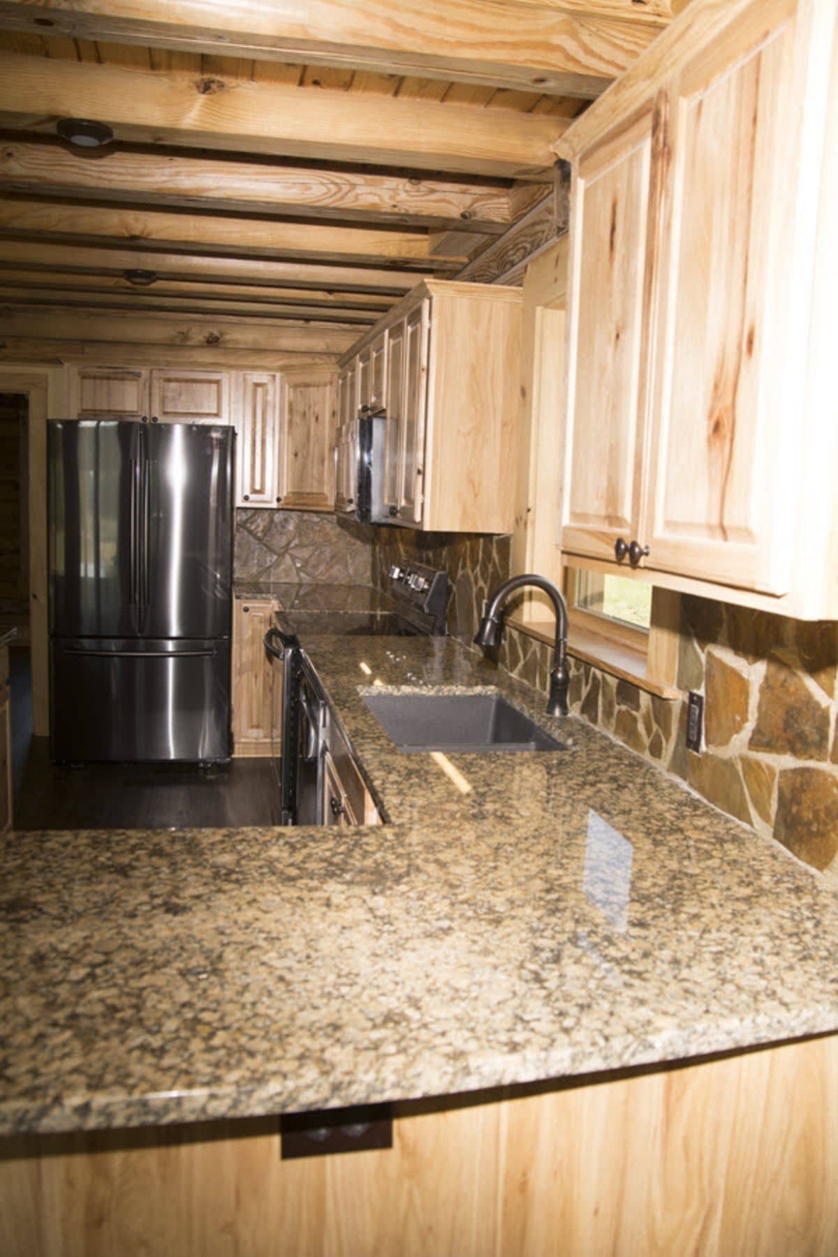kitchen counters below light wood cabinets with stainless steel refrigerator in background