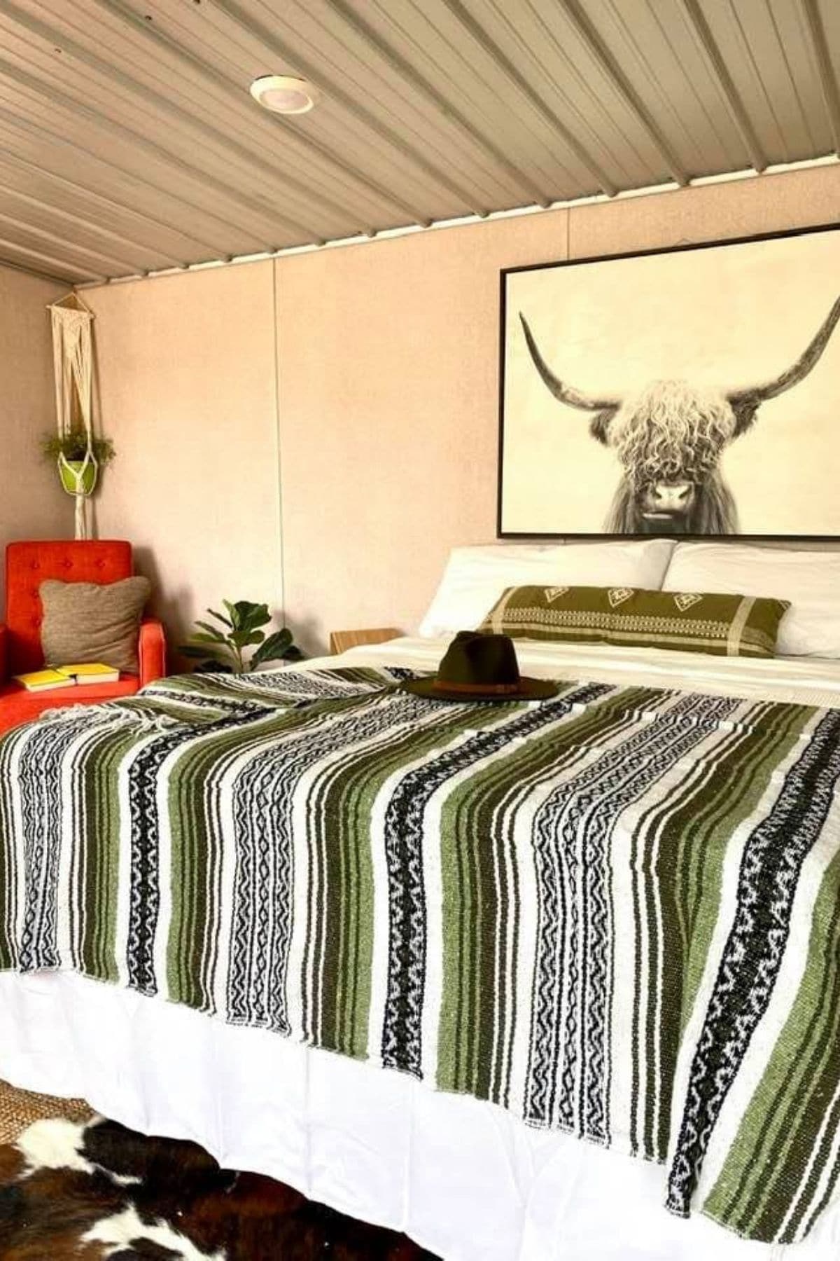 southwest styled blanket on end of bed with bull image on wall above bed
