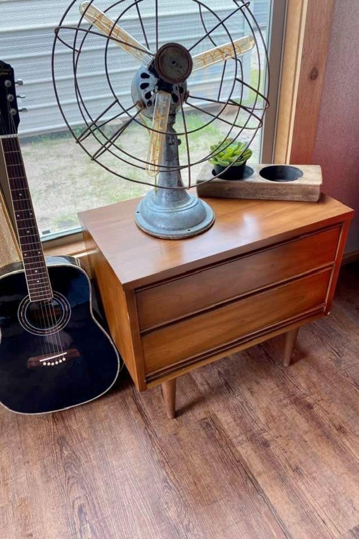 mid century modern chest of drawers in front of window by guitar