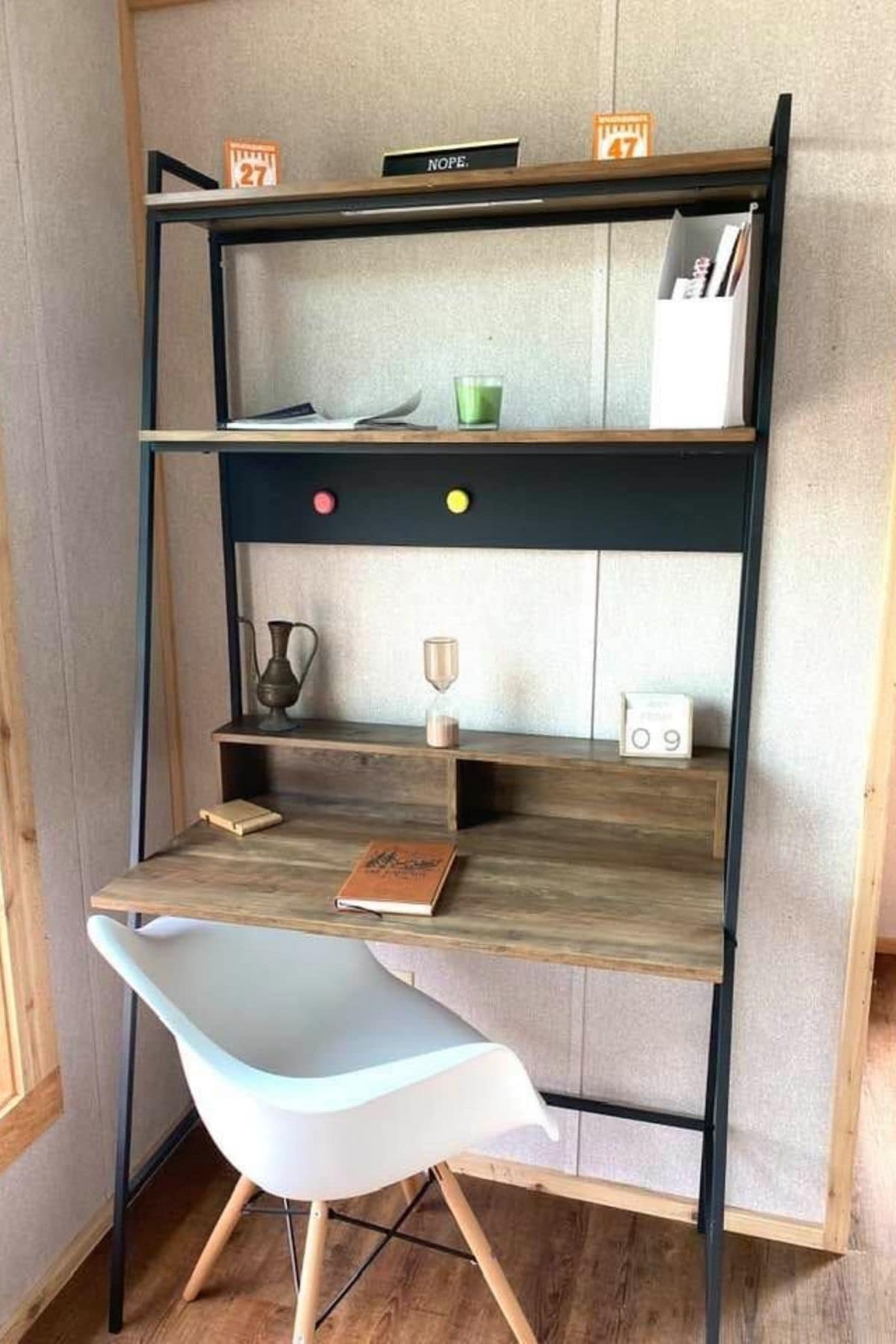 desk against wall with black and wood shelves and white chair