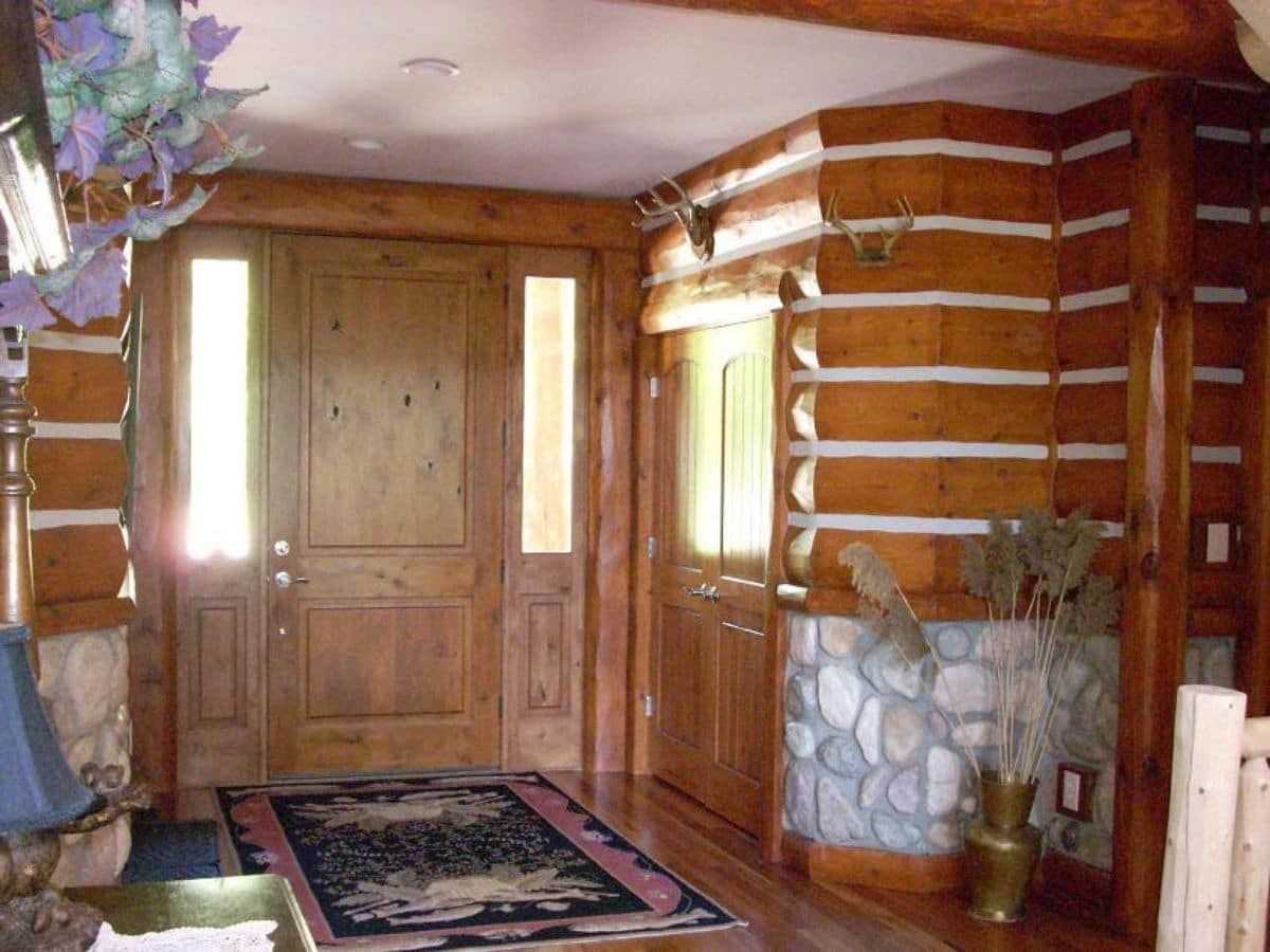front door to log cabin with stone accents on right of image