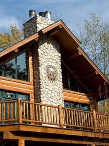 rock chimney on outside of balcony of log home