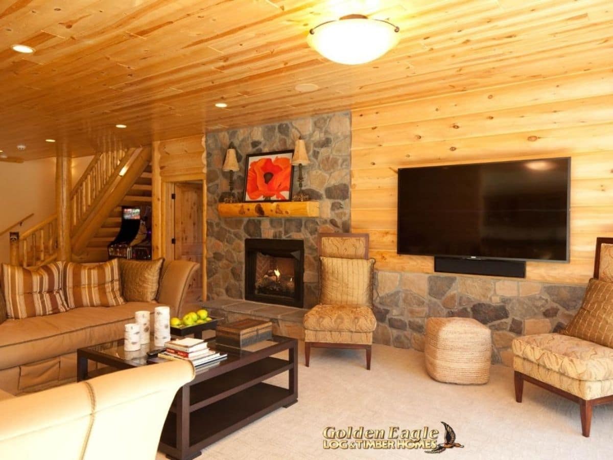 fireplace next to chairs and tv against log wall