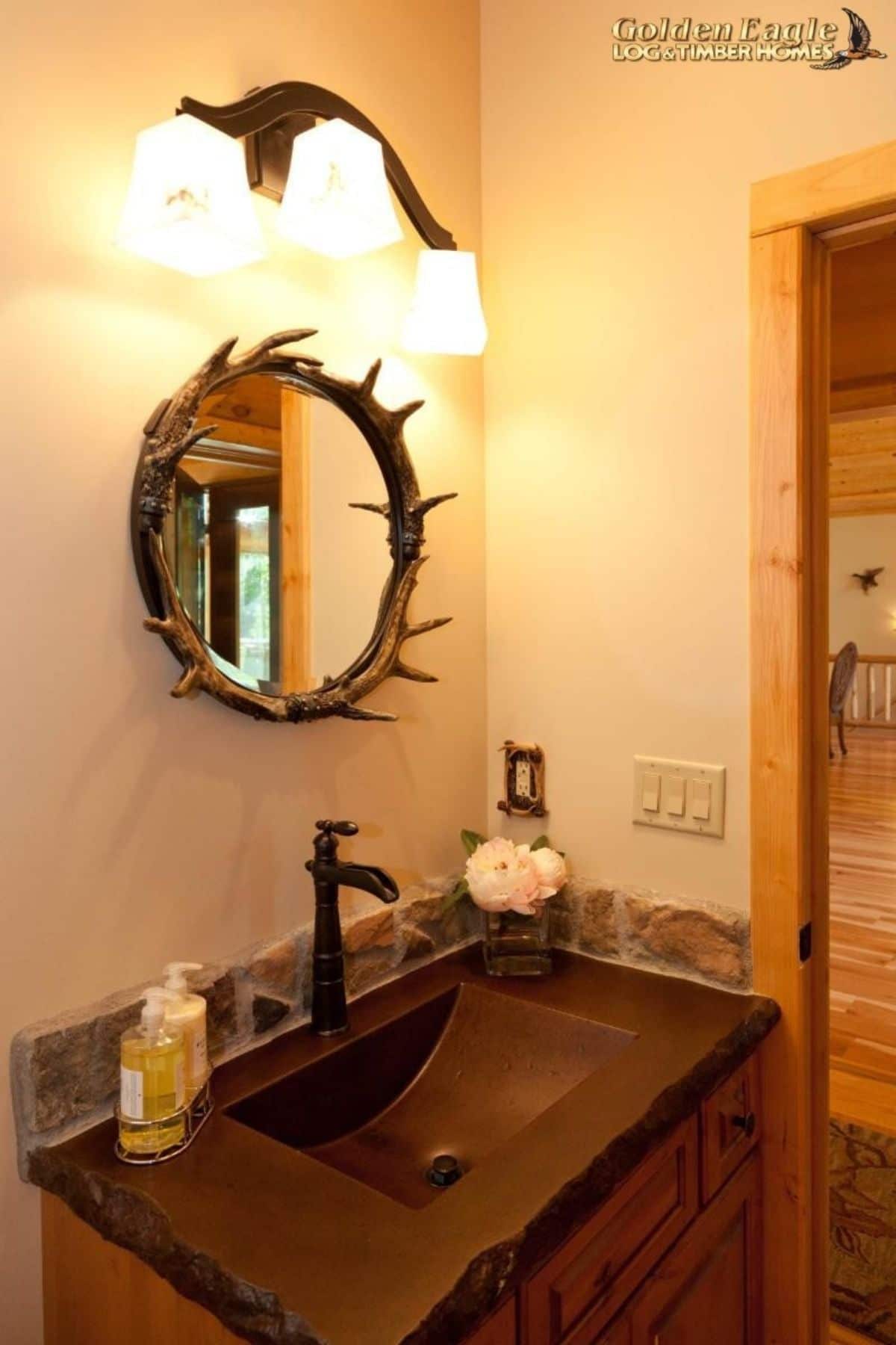 brown sink below antler framed mirror in bathroom
