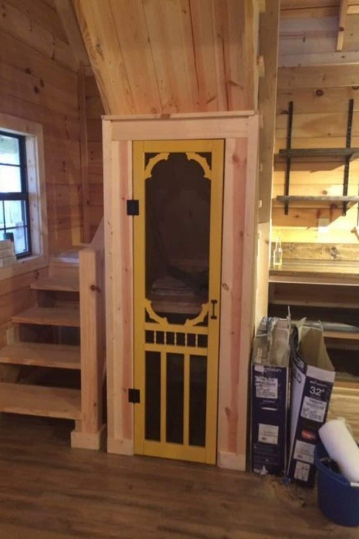 screen door opening by stairs and kitchen in cabin