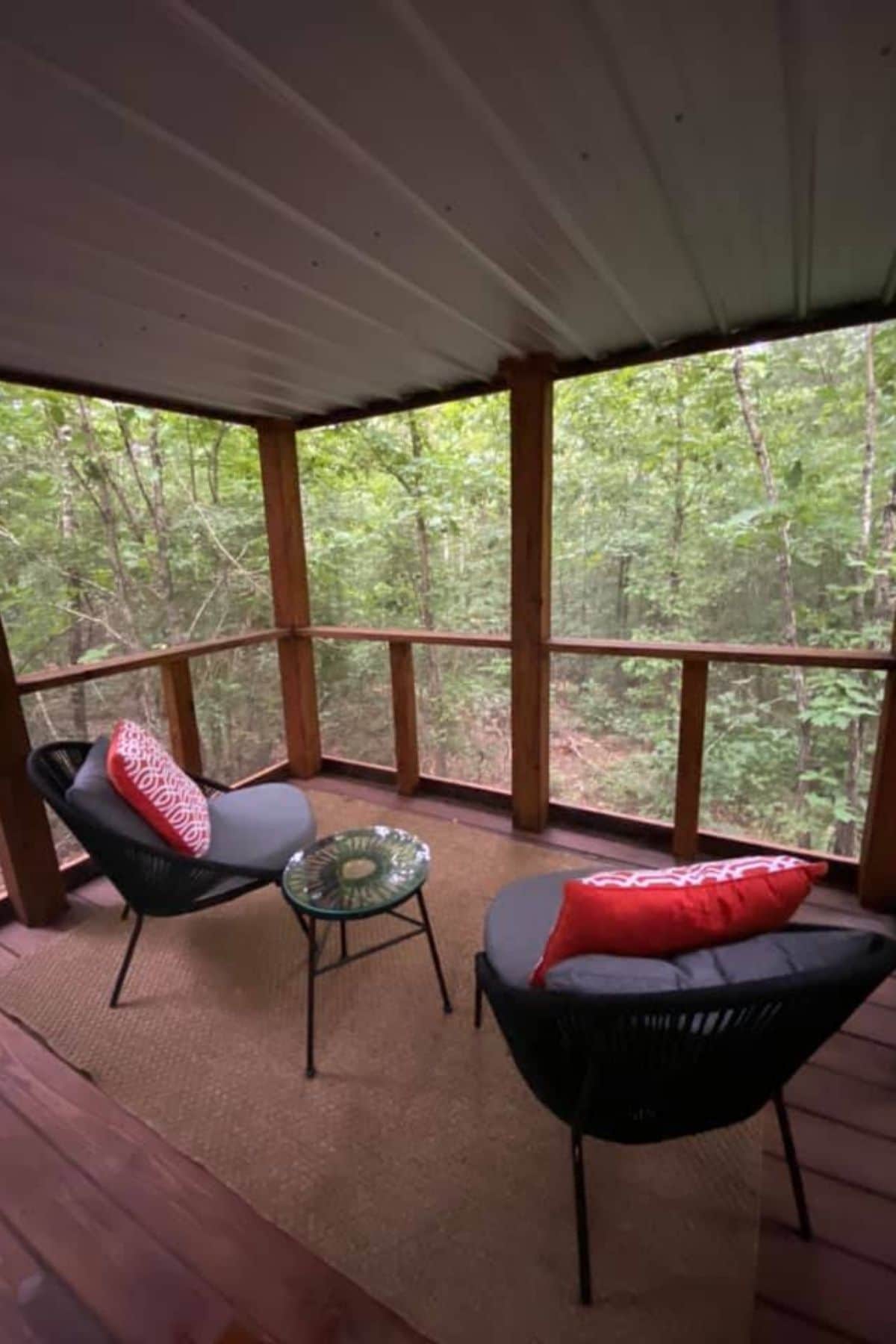 two black chairs in screened porch with red pillows