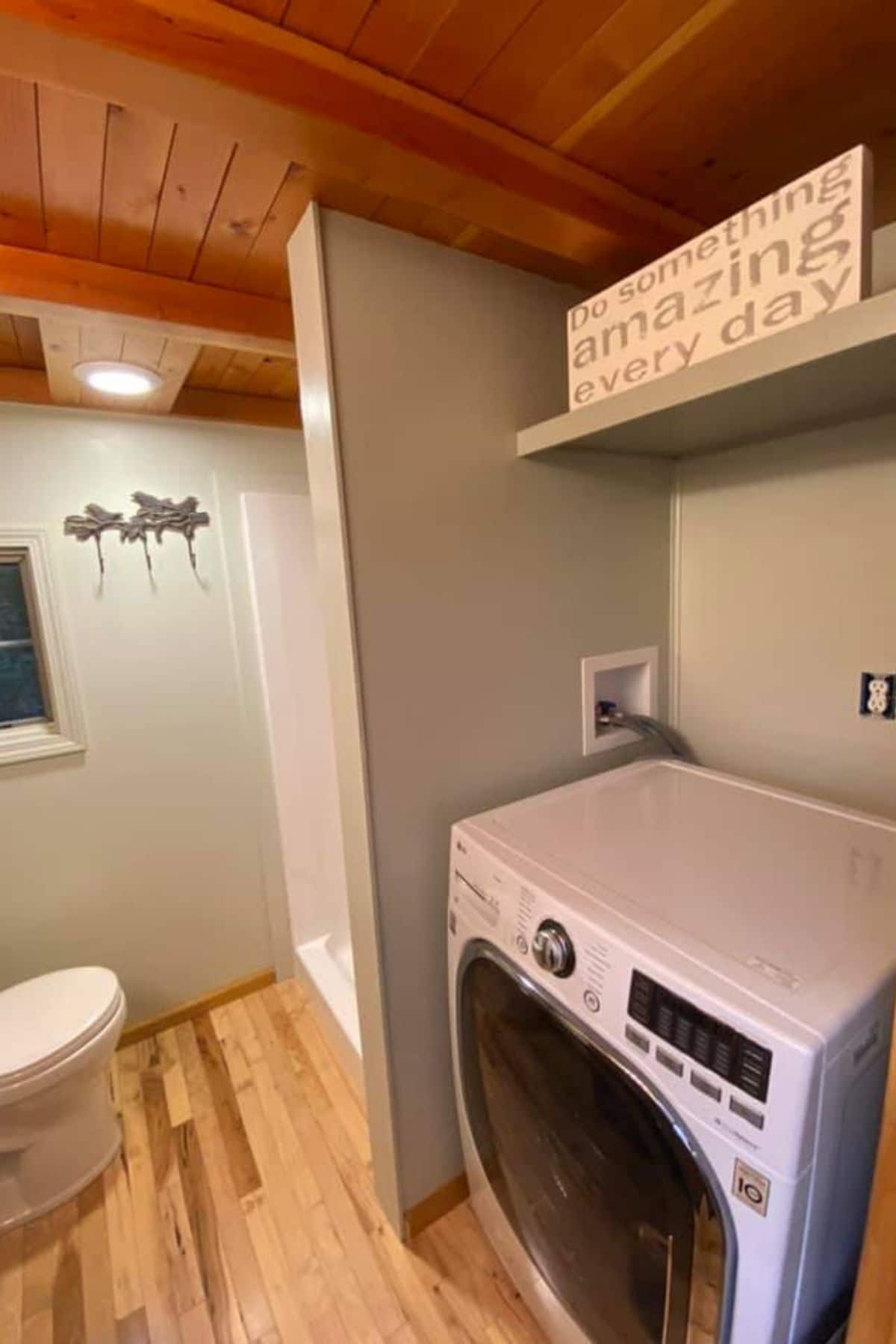 white combination washer and dryer in corner with shelf above