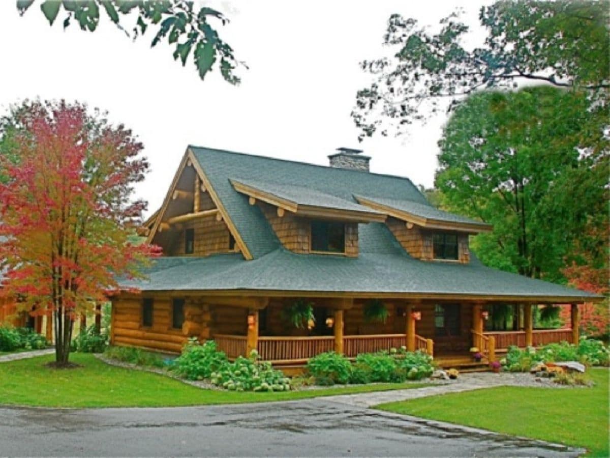 log cabin with wood porch and green roof
