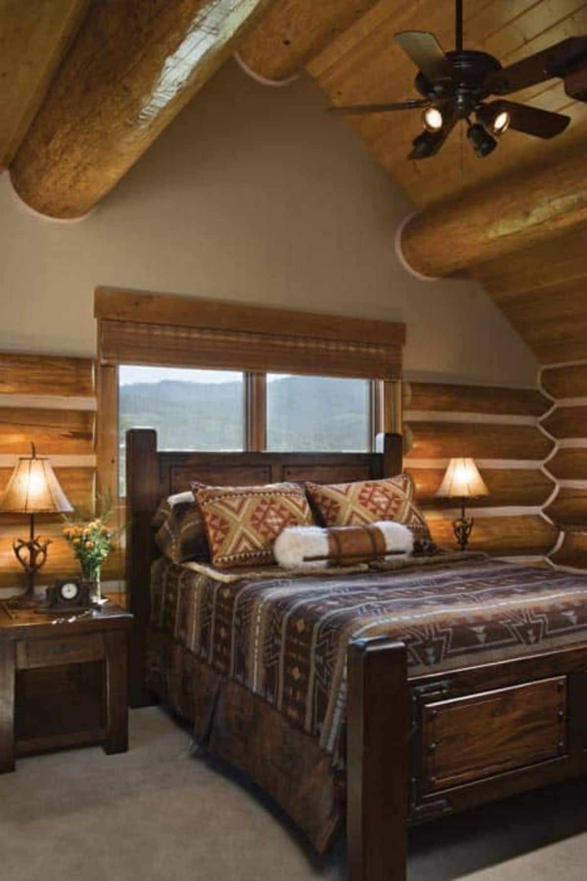 bed with brown blanket against window in log cabin room