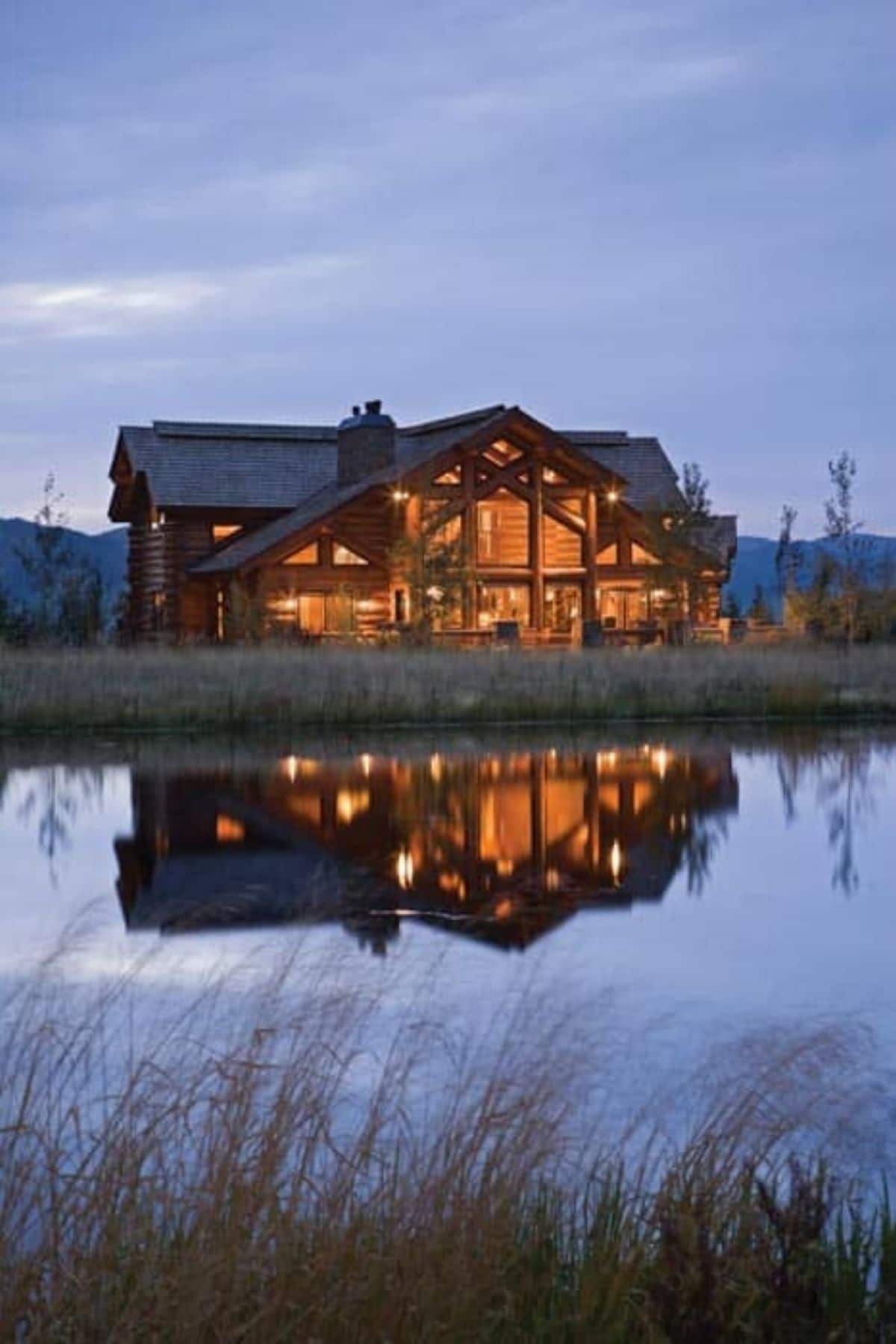 log cabin at sunset by river showing reflection on water