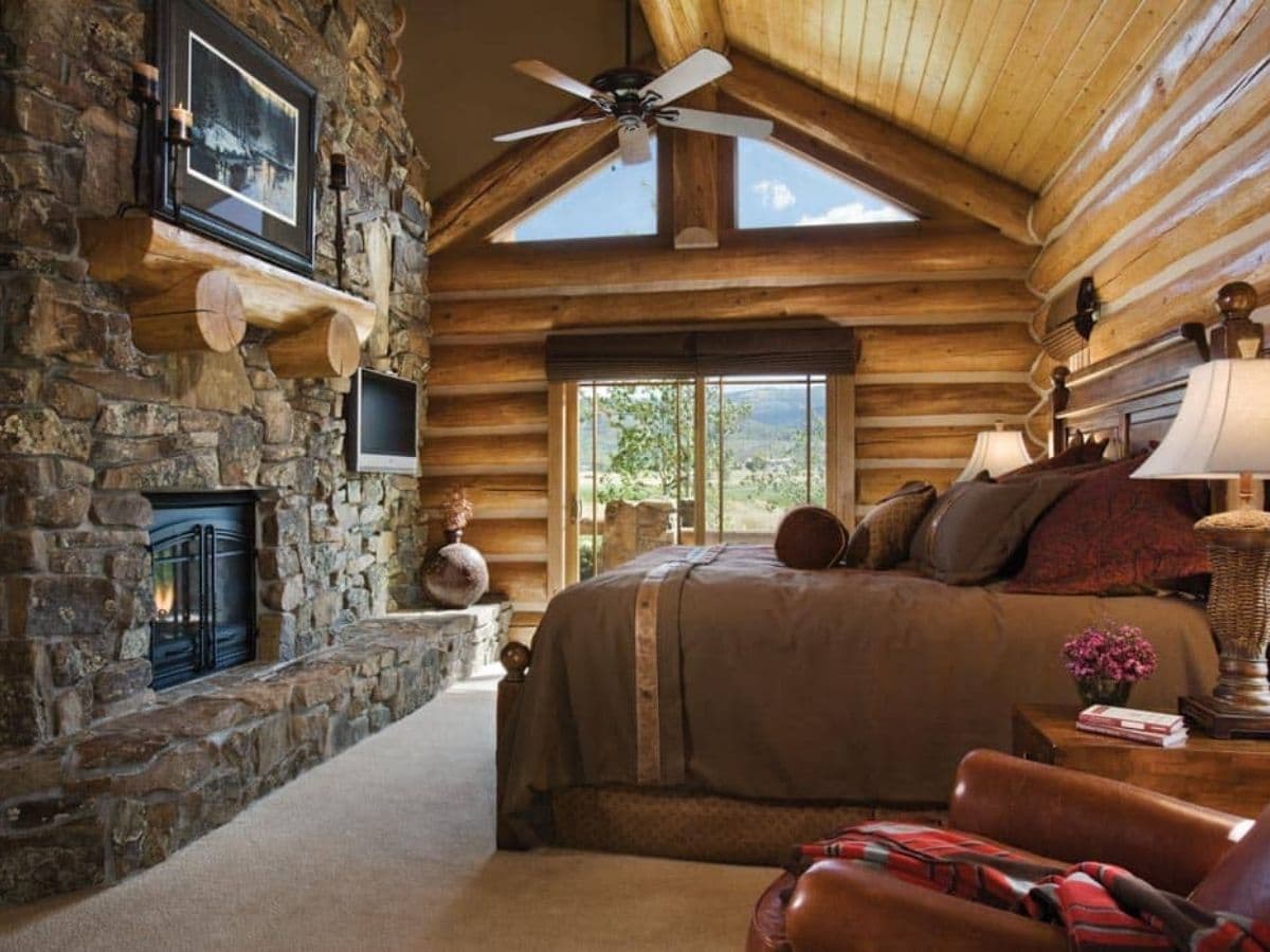 bed in log cabin with master fireplace