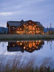 log cabin at sunset by river showing reflection on water