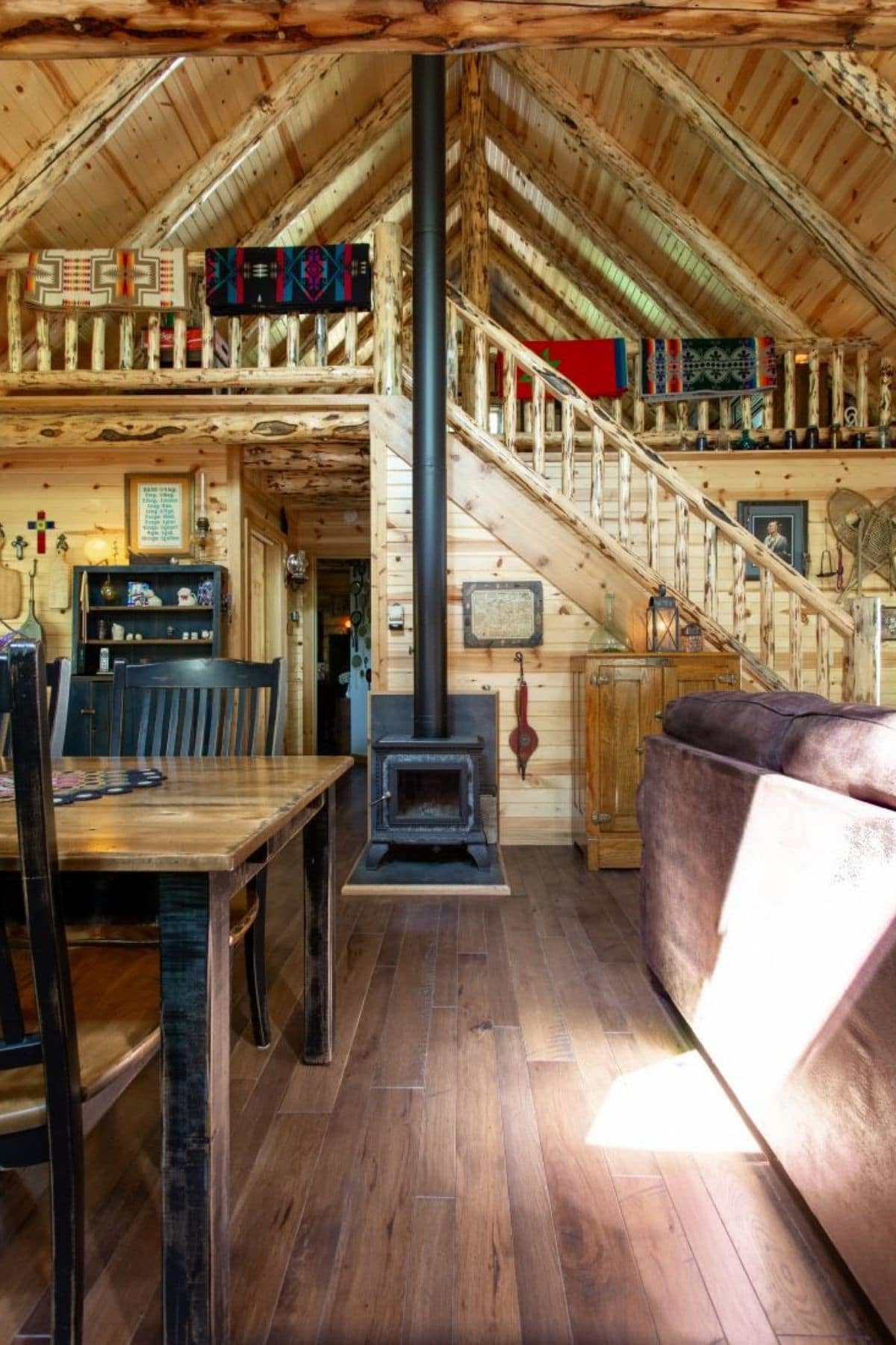 wood stove in front of stairs to loft with table and sofa in foreground