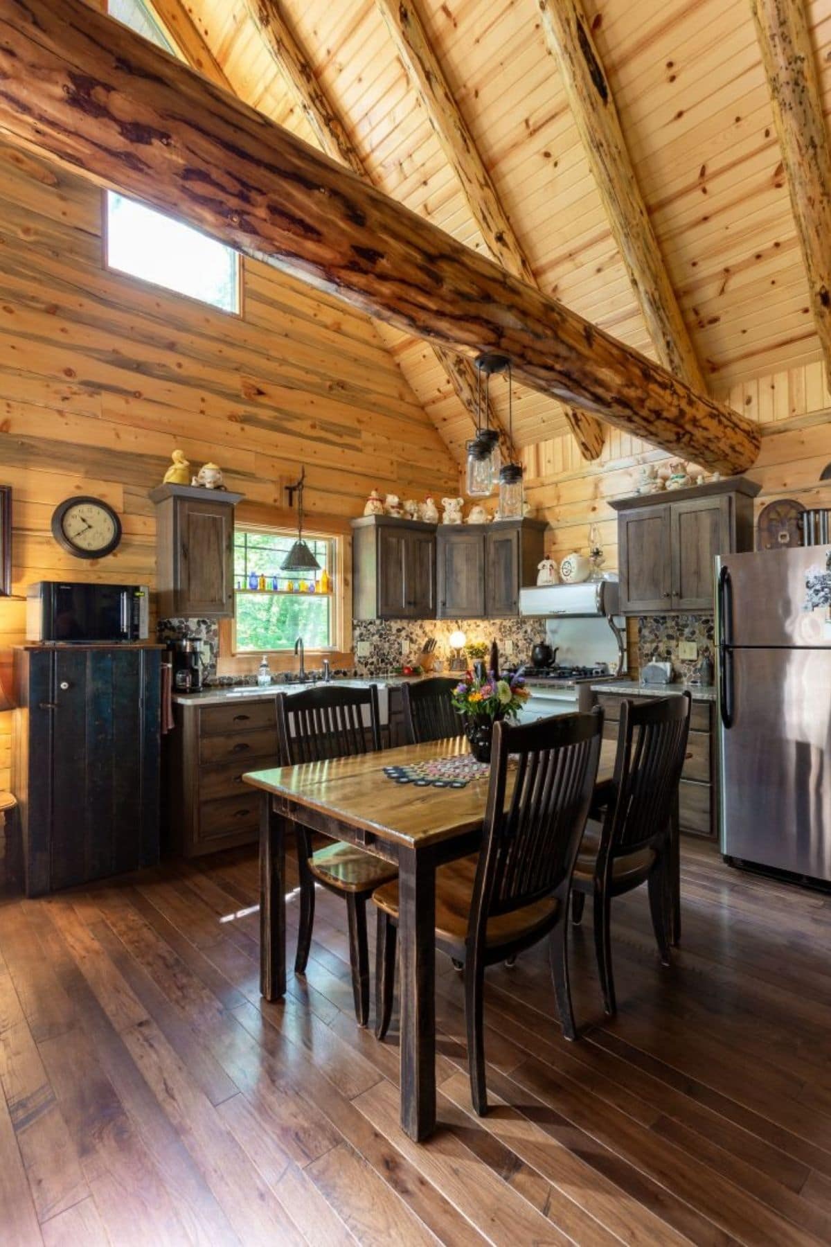 view into kitchen of log home with refrigerator on right and table in foreground