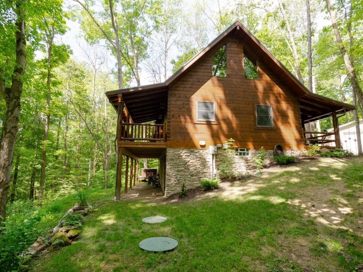 side of log cabin showing rock foundation and elevated porch on back