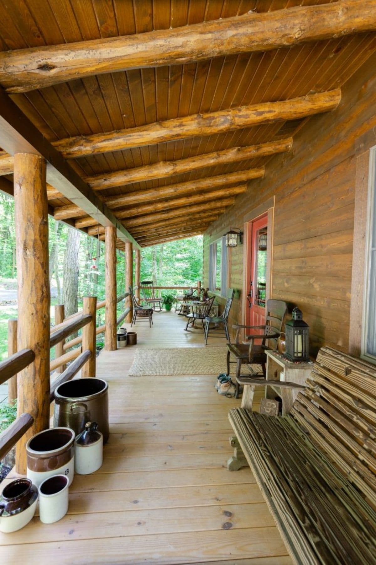 view down porch on log cabin with red door and bench seats