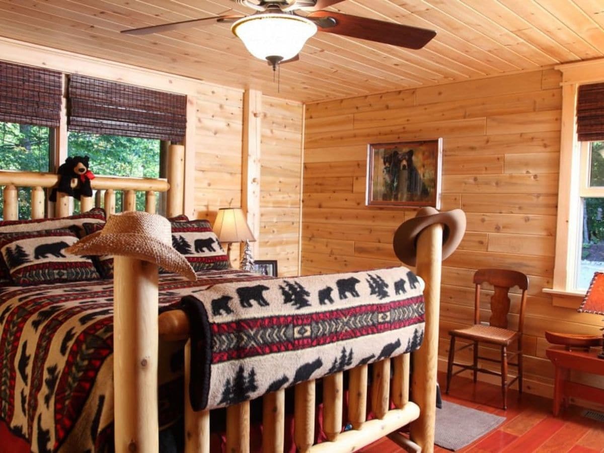 rustic log bed in room with red carpet and log cabin walls