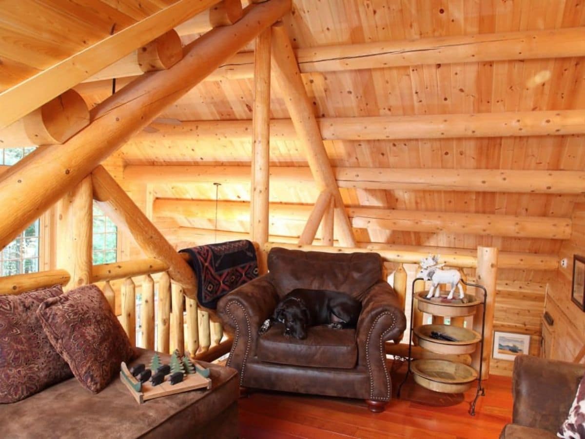 open loft space in log cabin with brown leather chair by wall