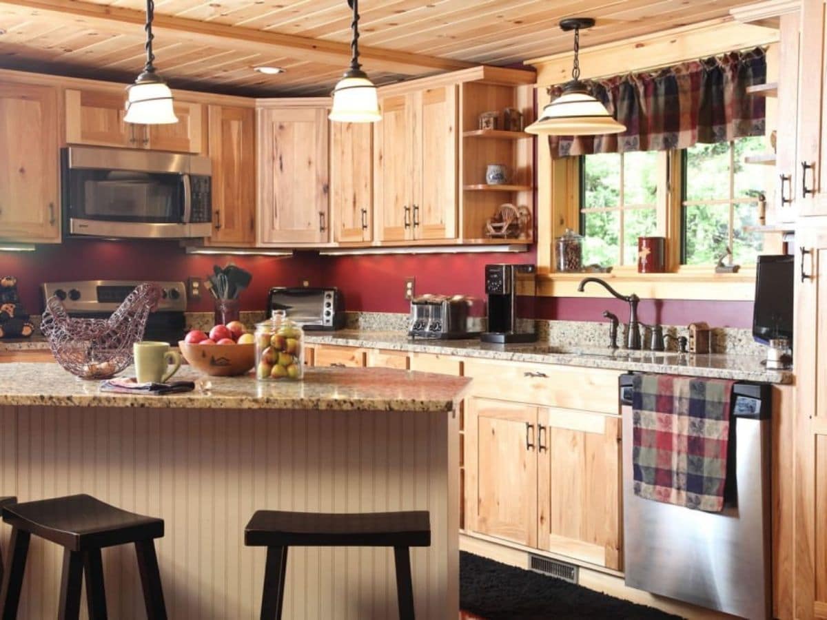 wood cabinets with red paint and wood island in foreground in kitchen
