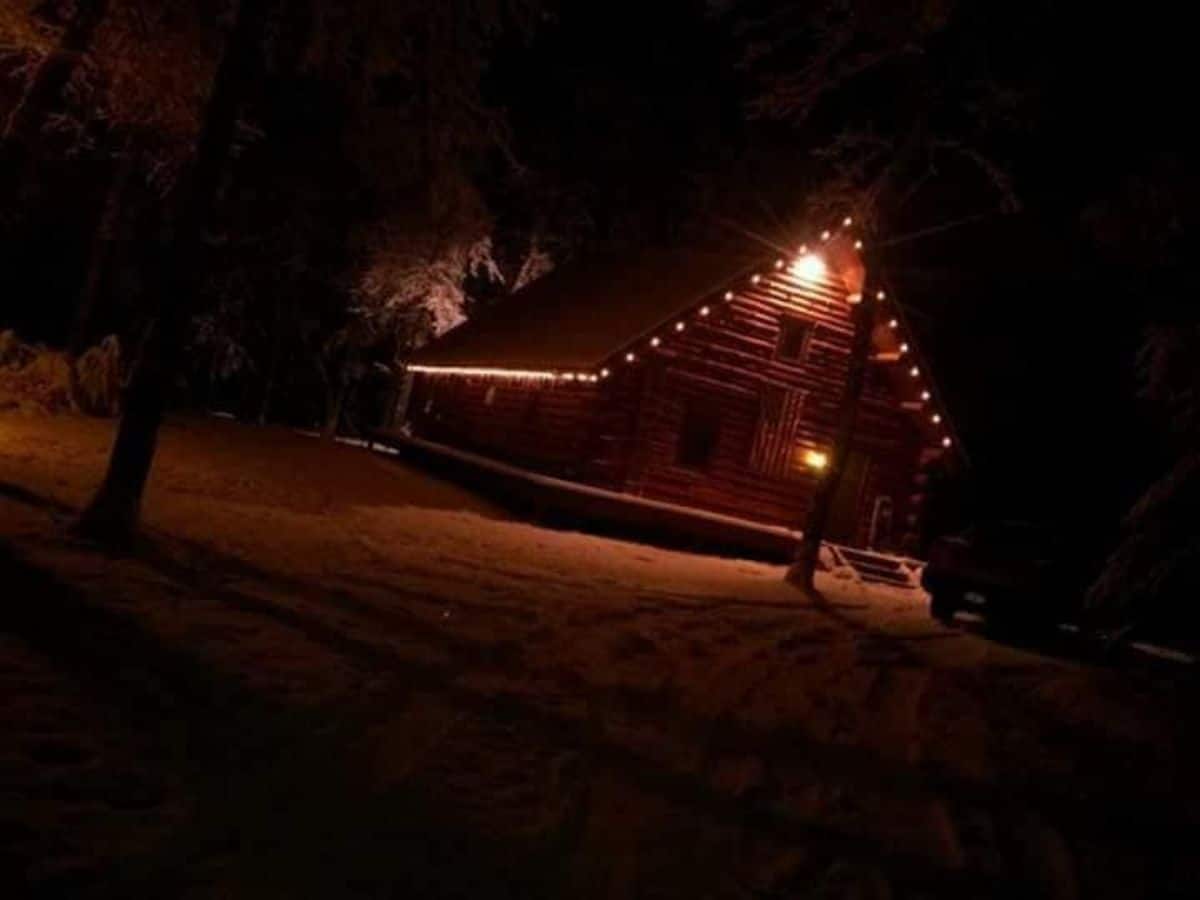 outside of cabin with lights on awning after dark