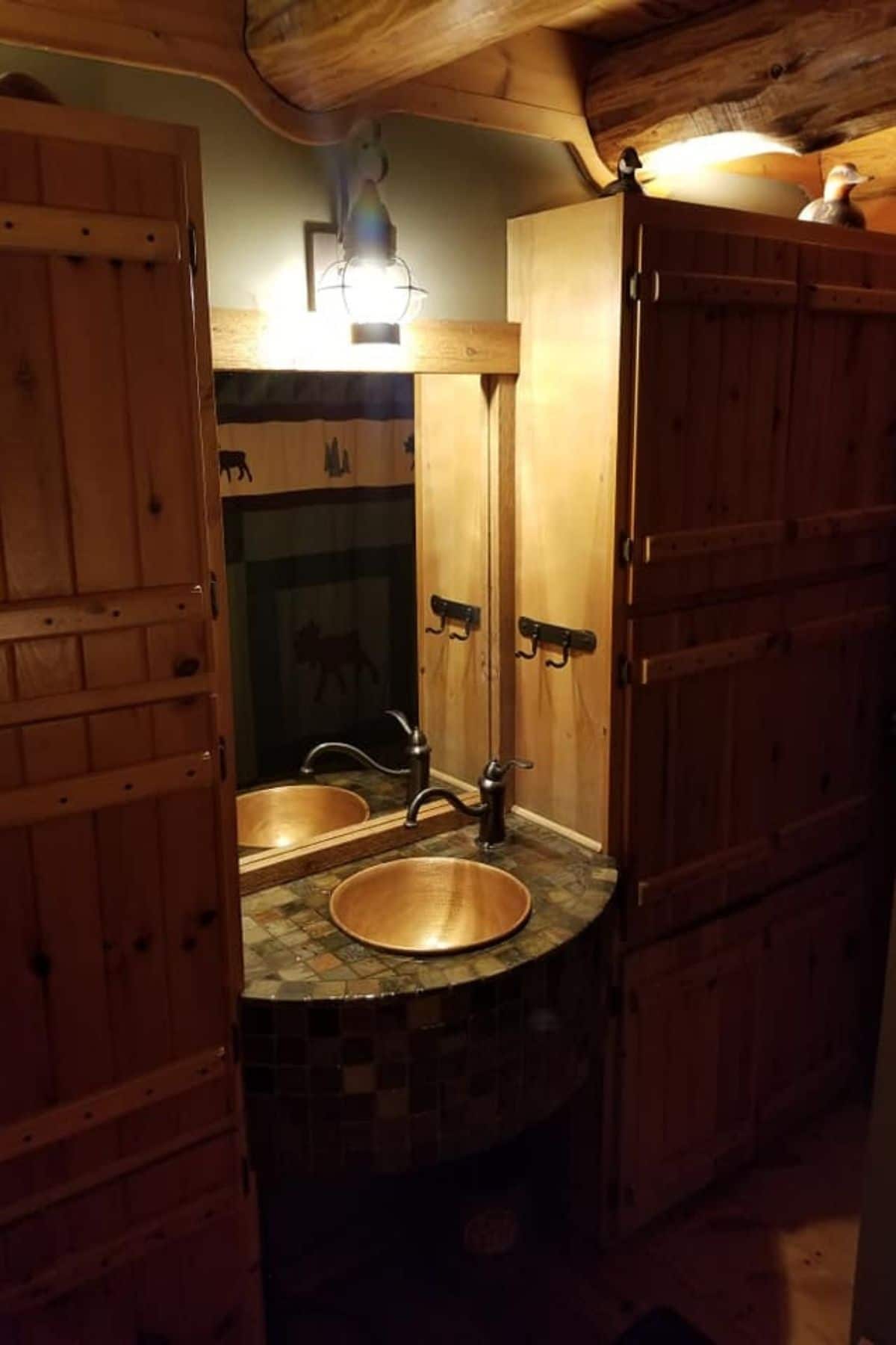 bowl sink in rock between two wood cabinets with mirror above