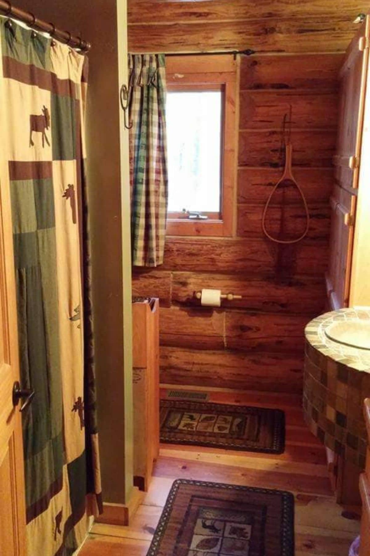 log cabin bathroom with green and cream shower curtain on left